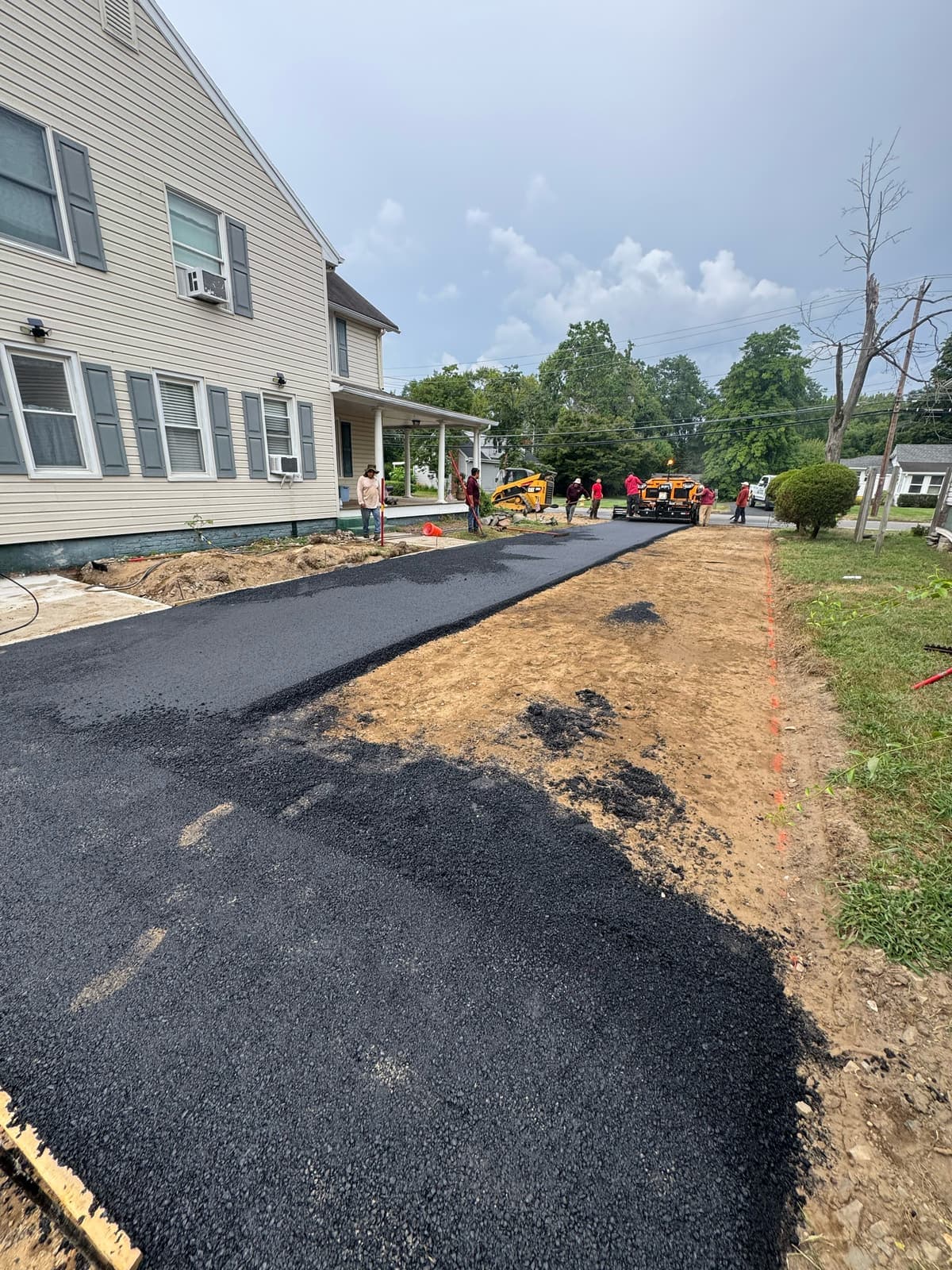 A new asphalt driveway running alongside a house after the old drive was dug out and rebased.