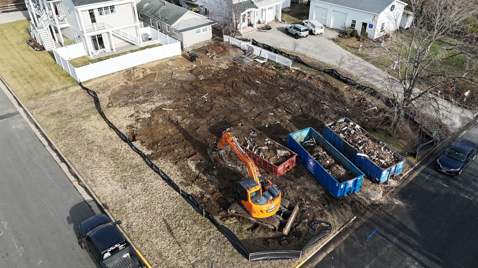 Aerial view of a residential lot being cleared, debris loaded into roll-off containers.